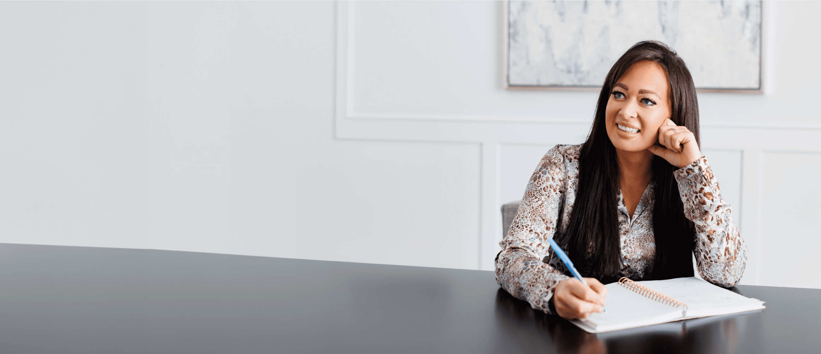 A picture of Thais smiling and looking away from the camera while writing a workbook.